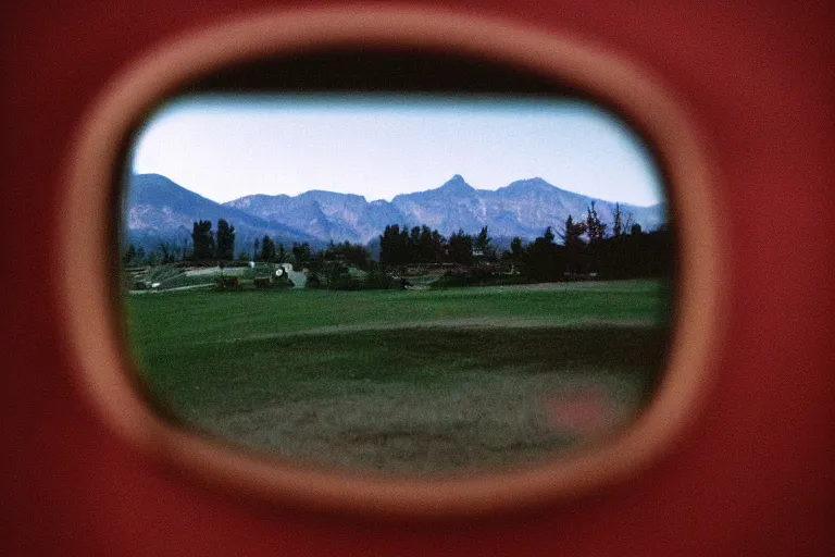 Prompt: film color photography, close-up mirror that reflected red at the green lawn, no focus, mountains in distance, 35mm