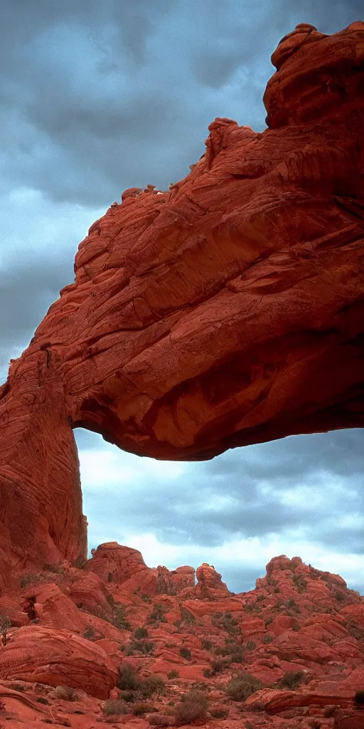 Image similar to an atmospheric film still by Ridley Scott with a huge towering dark gothic cathedral carved out of rock at the top of a red rock canyon