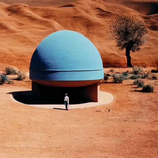 Image similar to a man standing outside a Non-Euclidean orb-like clay house sitting in the desert, vintage photo, beautiful cinematography, blue sky, film grain, James Turrell
