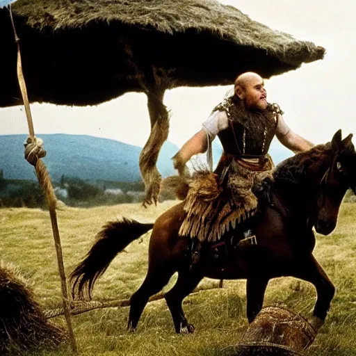 Prompt: Danny DeVito as a Hunnic barbararian on a horse, at the top of a hill overlooking a battleground campsite, film still