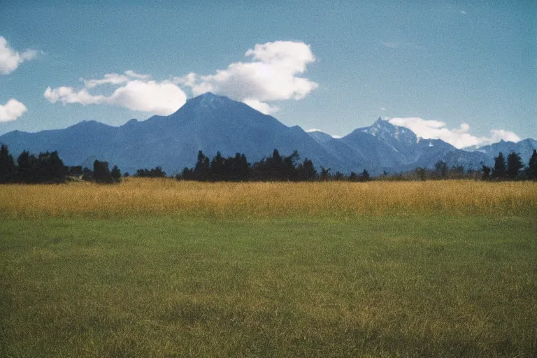 Image similar to film color photography, green lawn, small mirror reflected clouds, no focus, mountains in distance, 35mm