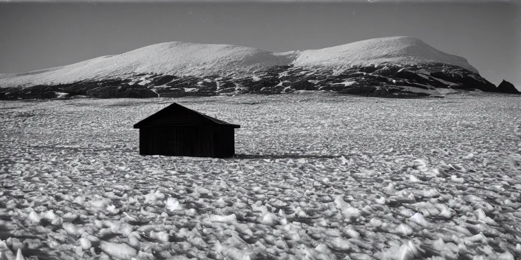 Prompt: A dark chapel at the base of a nunatak in a field of ice, monochrome photograph taken in 1910, grainy, film grain