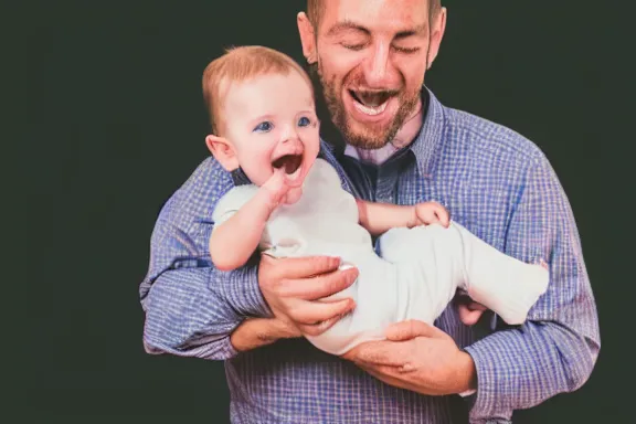 Prompt: a very happy man holding a baby by its leg