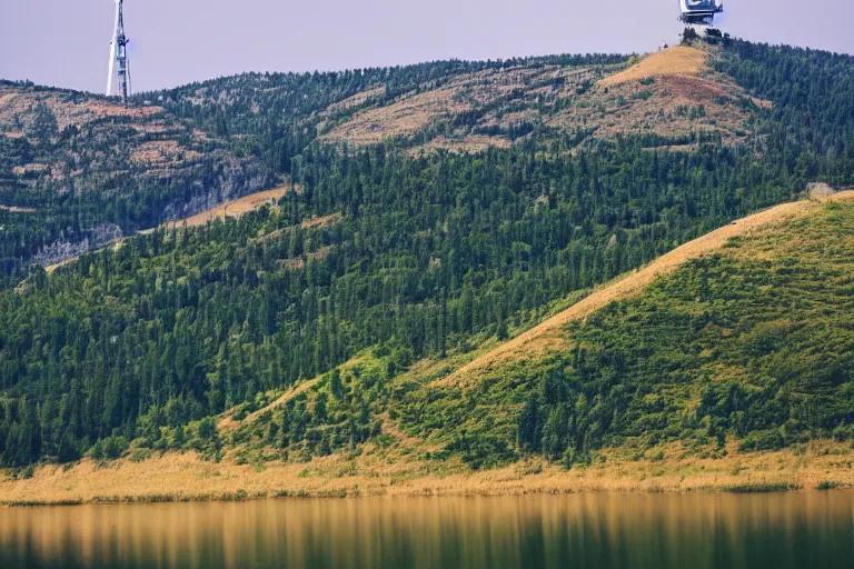 Prompt: a hill with a radio tower next to a lake, hills in background. telephoto lens photography.