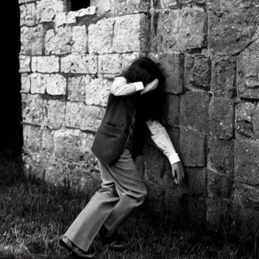 Image similar to An utterly terrified young man with long hair in 1930s attire cornered with his back against a stone wall. Scared look, panic, horror