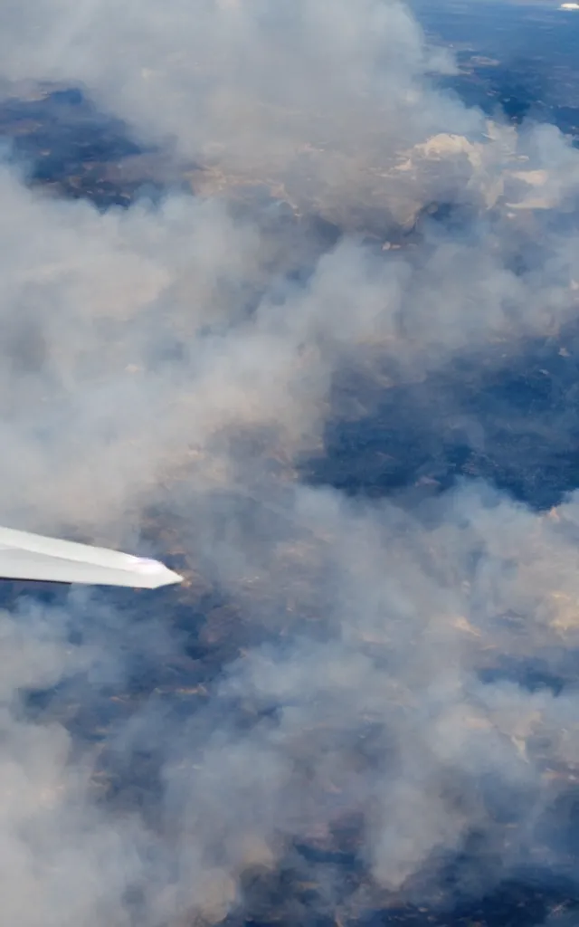 Prompt: a photograph out of a plane window, the plane engine is burning