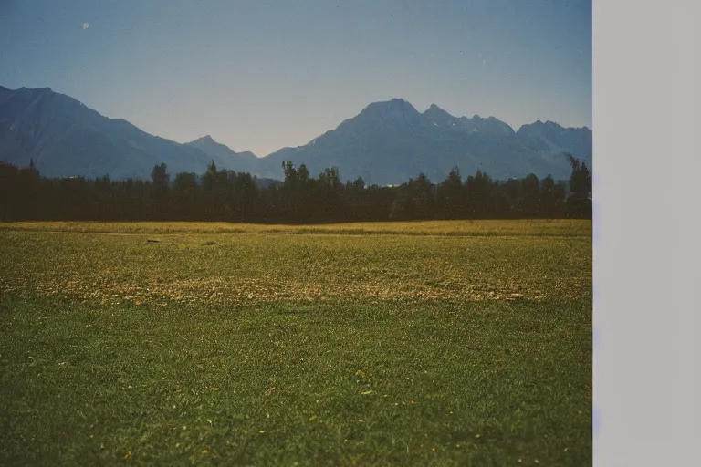 Prompt: film color photography, small mirror in distance, long view of green lawn, no focus, mountains in distance, 35mm