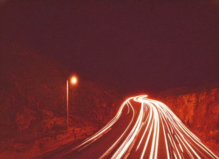 Image similar to pov headlights of a car illuminate a strange dark canyon road, it's the dead of night, in a distance the bright city lights glow, cinematic, cinestill