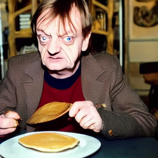 Image similar to mark e smith sitting at a table eating a big stack of pancakes, fork and knife in hand, drooling and licking his lips, photograph