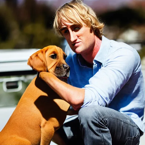 Image similar to 50mm photo, Owen Wilson saying wow holding a boxer puppy