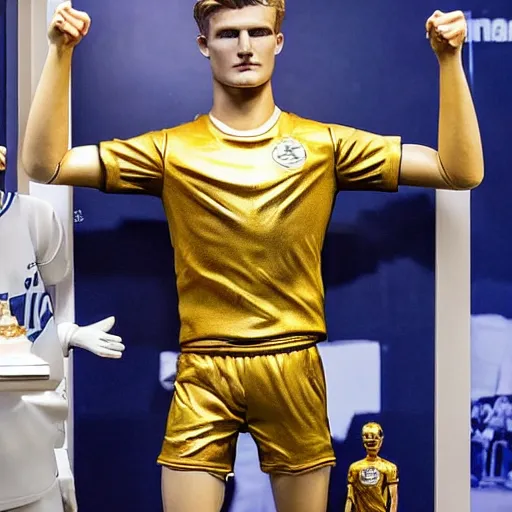 Image similar to a realistic detailed photo of a guy who is an attractive humanoid who is half robot and half humanoid, who is a male android, soccer players martin ødegaard & timo werner, shiny skin, posing like a statue, blank stare, in a living room, on display, showing off his muscles, gold soccer shorts, no jersey, statue, many copies of them