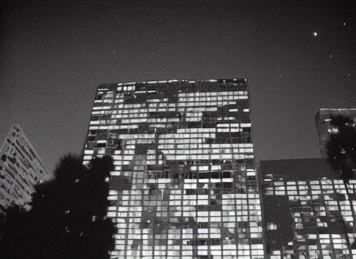 Image similar to looking up at a sprawling building complex seen from a dark parking lot in los angeles at night. 1 9 9 0 photo by james cameron