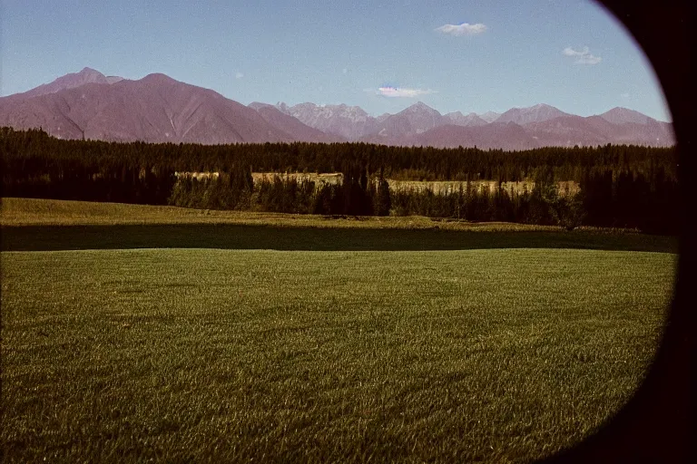 Image similar to film color photography, small mirror in distance, long view of green lawn, no focus, mountains in distance, 35mm