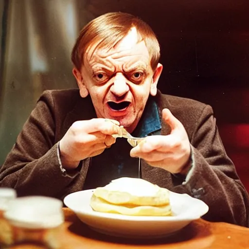 Prompt: mark e smith sitting at a table eating a big stack of pancakes, fork and knife in hand, drooling and licking his lips, photograph