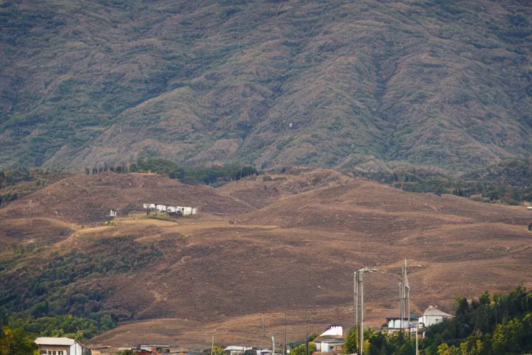 Image similar to looking down a road with warehouses on either side. hill background with radio tower on top. telephoto lens compression.