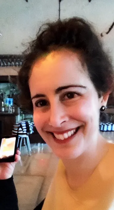 Prompt: Sappho smiling in a selfie at a new restaurant, iPhone photo