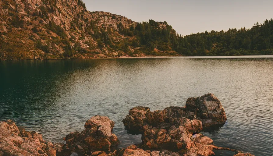 Image similar to cinematic wide shot of a lake with a rocky foreground, sunset, a bundle of rope is in the center of the lake, leica, 2 4 mm lens, 3 5 mm kodak film, f / 2 2, anamorphic