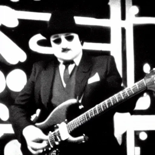 Image similar to john belushi wearing a black suit and black necktie and black fedora playing electric guitar in a darkened nightclub, 3 5 mm film still from 1 9 8 1, grainy.