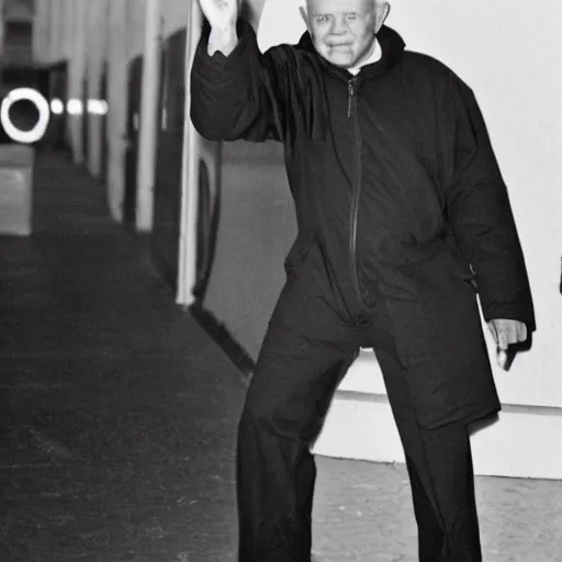 Image similar to john paul ii standing in a black hoodie, black cargo pants and high black boots, evening time, dark