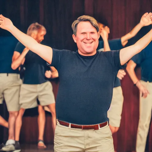 Image similar to a middle aged gentleman with brown moptop hair and red cheeks is doing the chicken dance. he is clean - shaven. he is wearing a dark blue tshirt and khaki shorts. he holds his arms out like they are folded wings and dances animatedly. he has no beard or moustache.