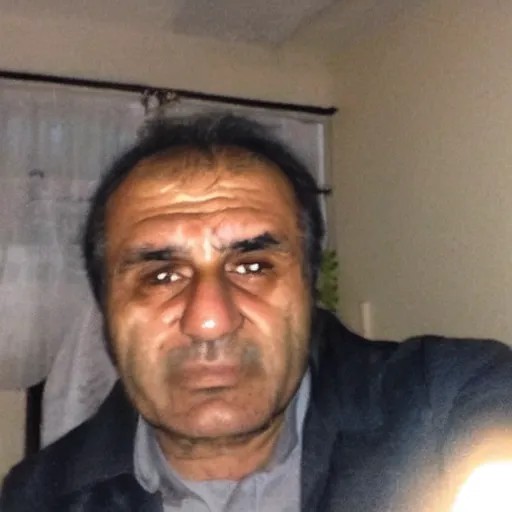 Image similar to my Kurdish dad accidentally taking a selfie with the front camera, squinting because the camera flash is so bright in his face