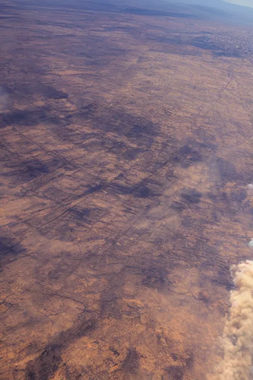 Image similar to airplane window view, flying above a drying landscape and huge fire